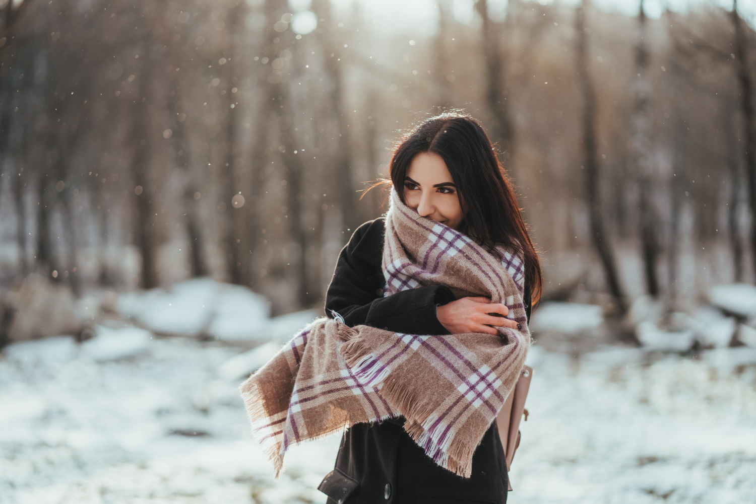 Vrouw met lang haar en een sjaal wilt warm blijven tijdens de winter